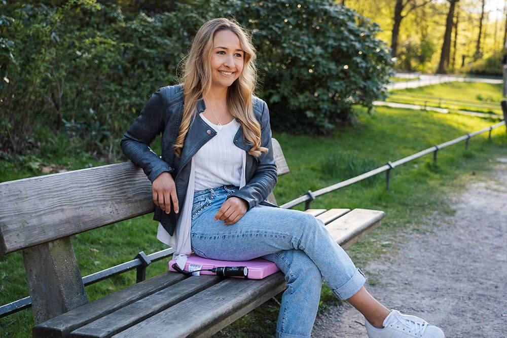 Donna seduta in giardino con il suo cuscinetto riscaldante rosa